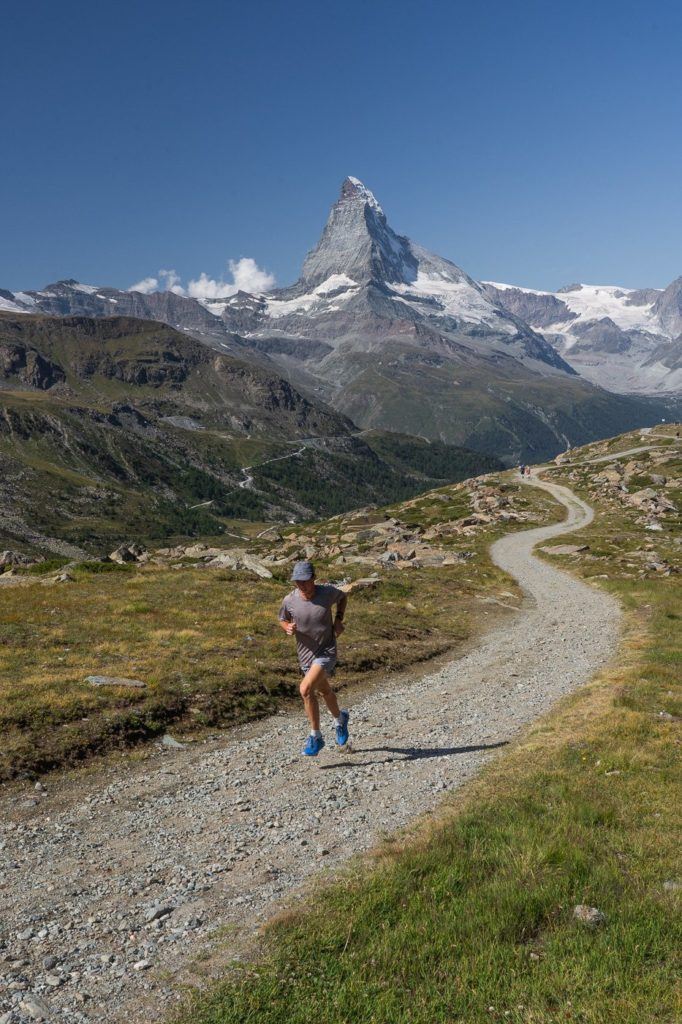 a man running on a trail in the mountains.