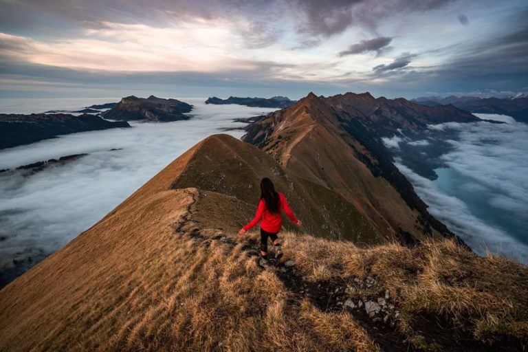 a woman standing on top of a mountain above the clouds.