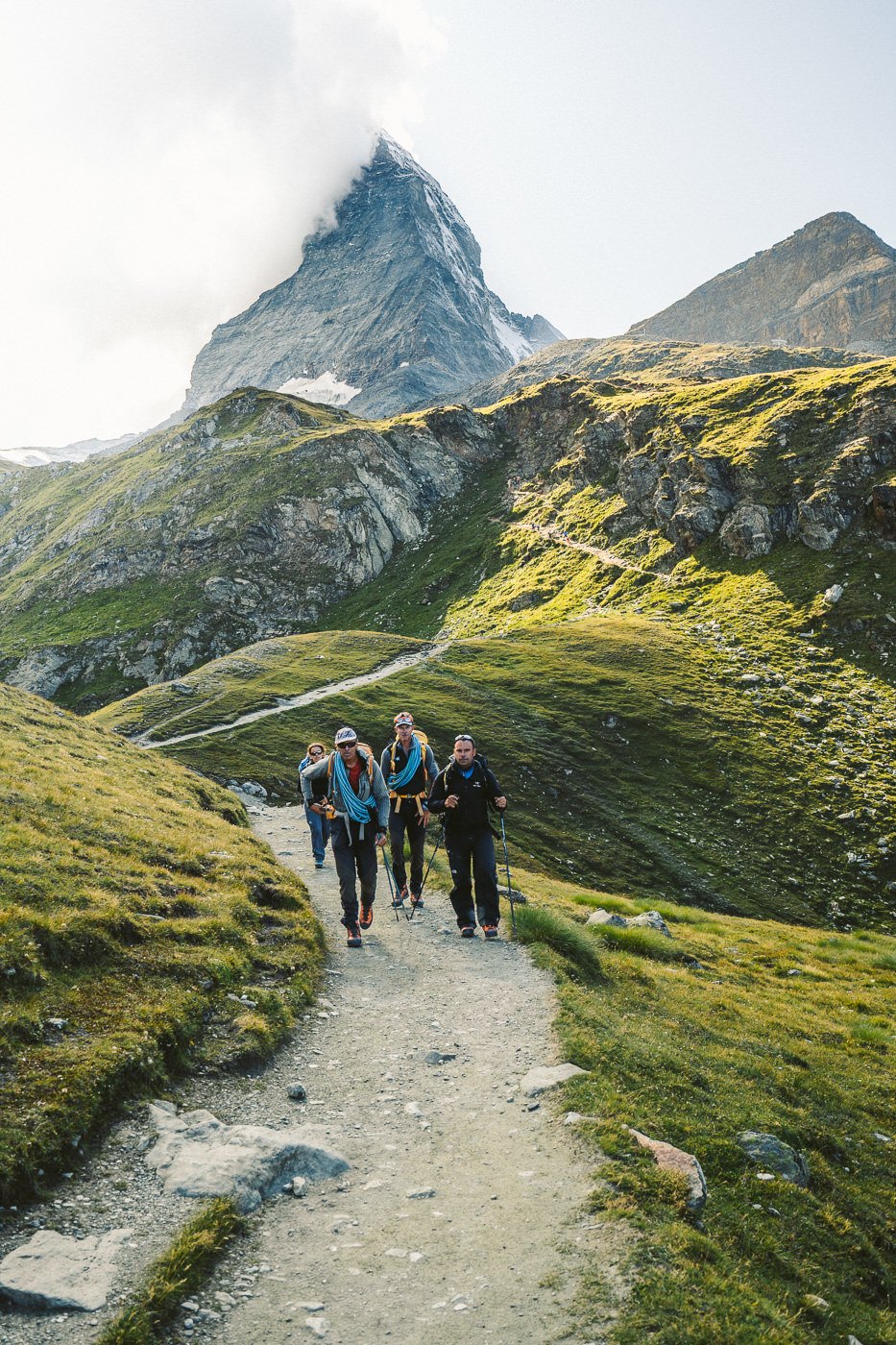 a group of people walking up a path in the mountains.
