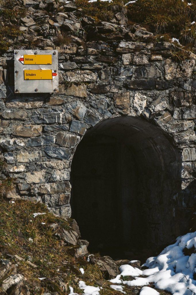 a stone tunnel with a yellow sign on it.