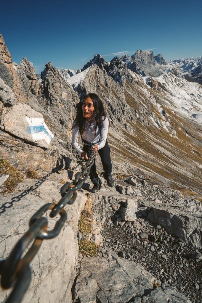 a woman standing on top of a mountain next to a chain.