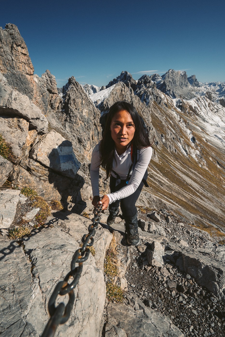 a woman is climbing up a mountain with a chain.
