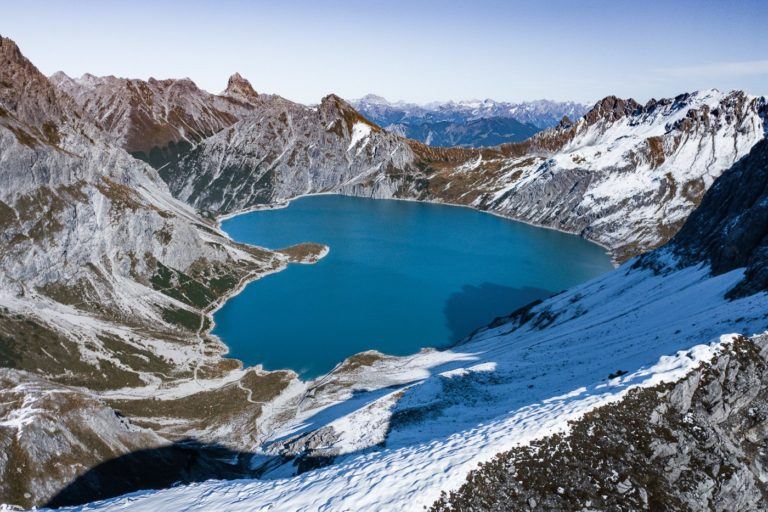 a blue lake surrounded by snow covered mountains.