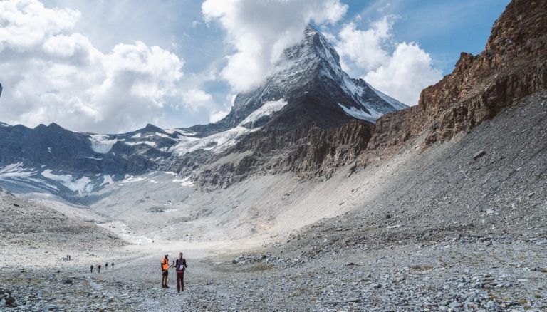 a group of people walking across a rocky field.
