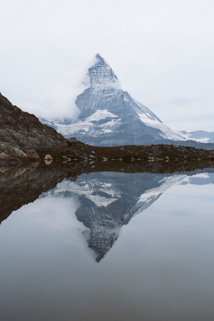 a mountain is reflected in the water of a lake.