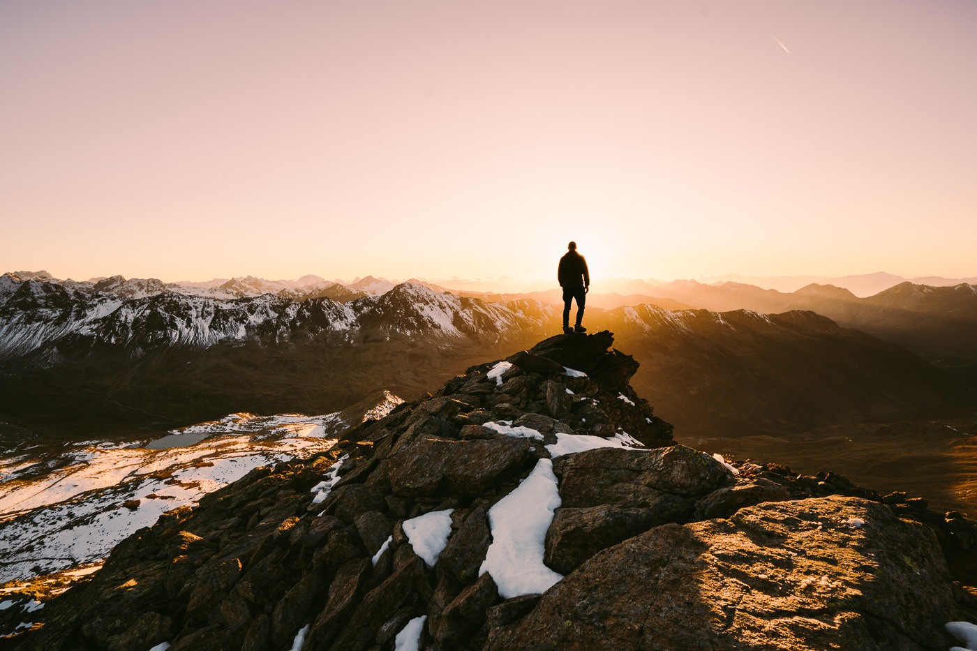 a person standing on top of a mountain at sunset.