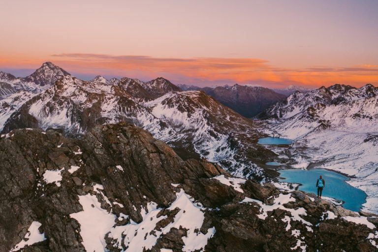 a couple of people standing on top of a snow covered mountain.