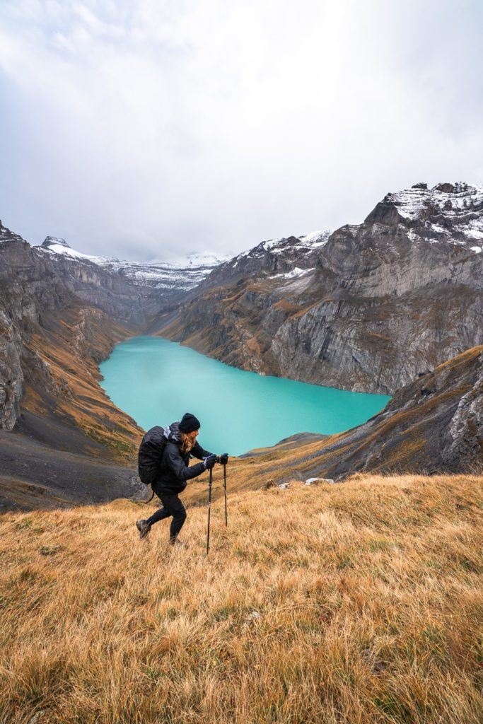 a man hiking up a hill with a lake in the background.