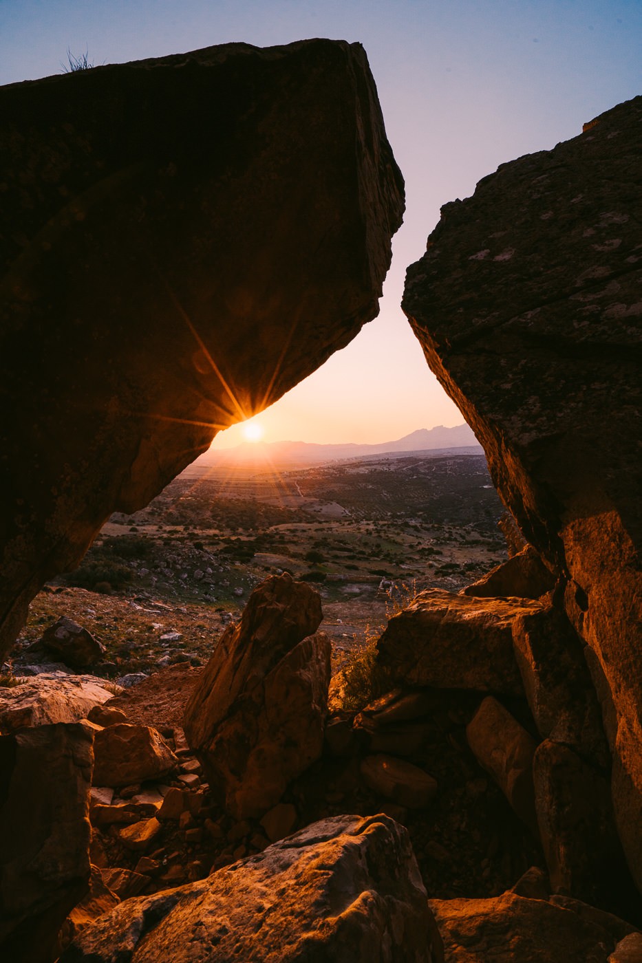 the sun is setting behind a rock formation.