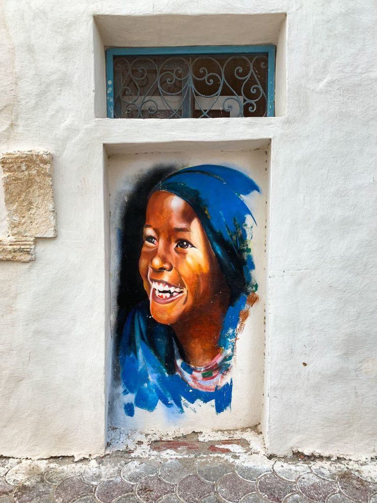 a painting of a smiling woman on the side of a building.