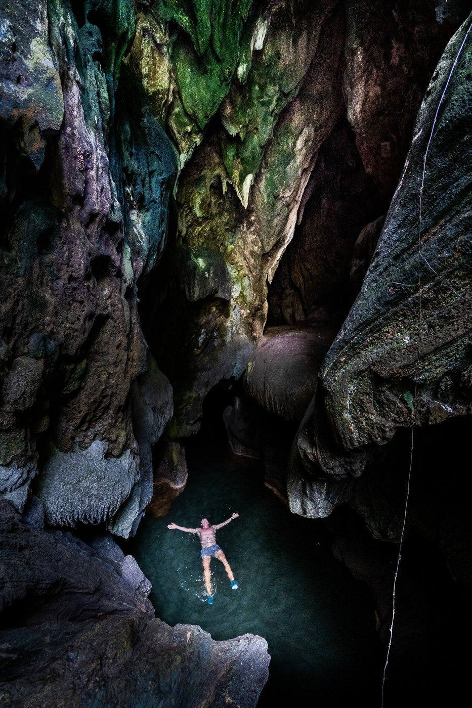 a person swimming in a pool of water in a cave.