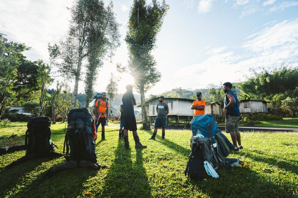 a group of people standing in a field with backpacks.