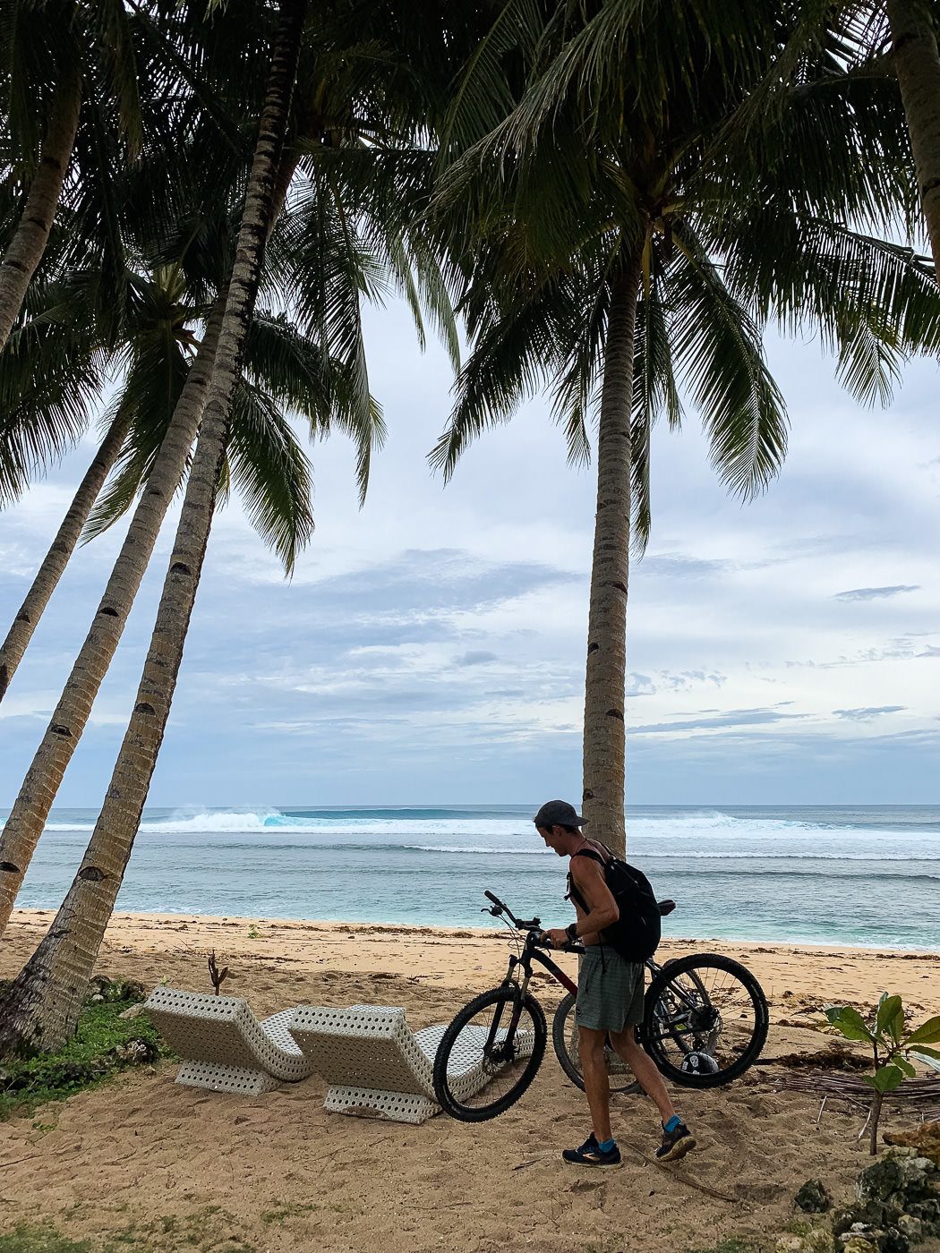 a man standing next to a bike on a beach.