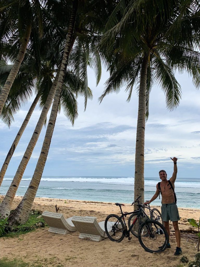 a man standing next to a bike on a beach.
