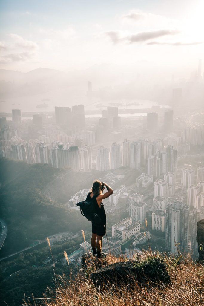 a woman standing on top of a hill overlooking a city.