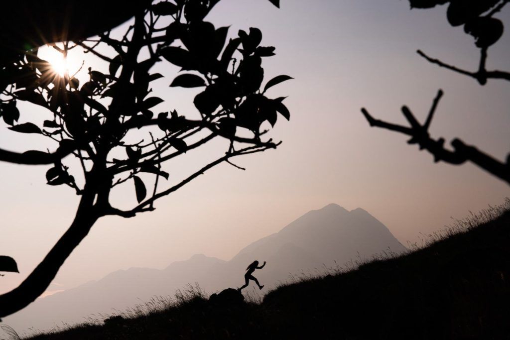 a silhouette of a person running on a hill.