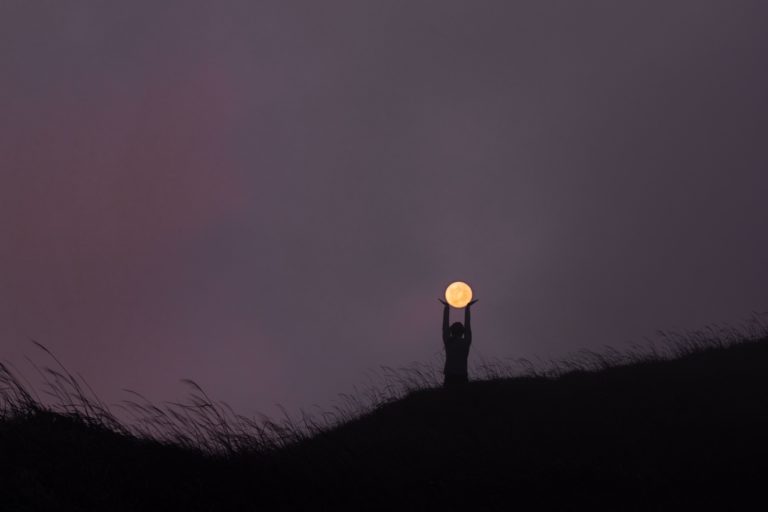 a person standing on top of a hill holding a light.