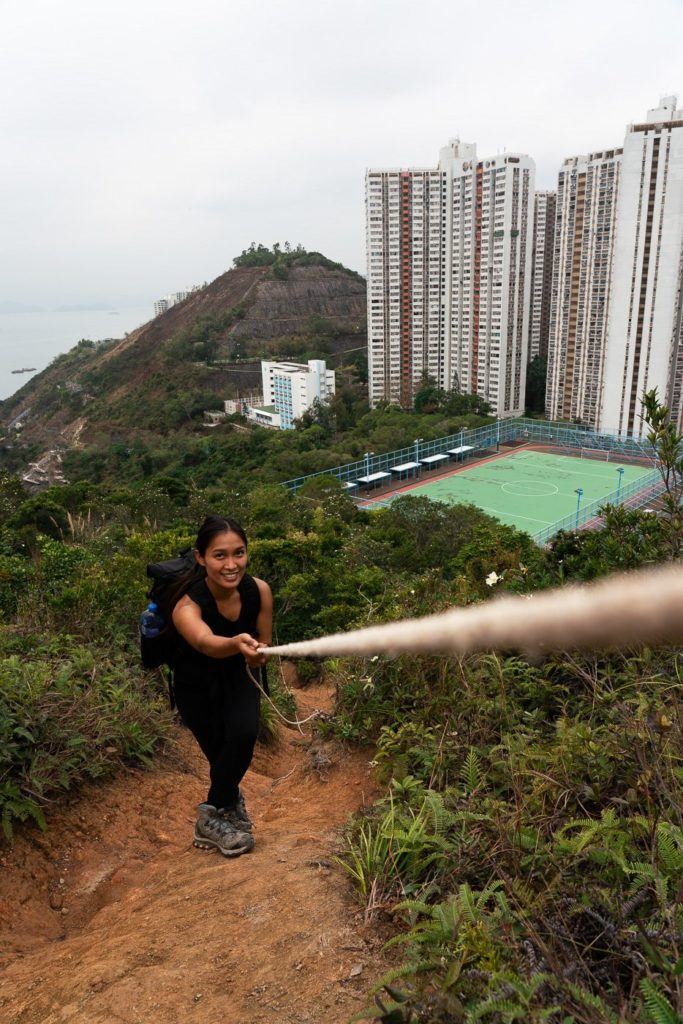 a woman with a backpack is walking up a hill.