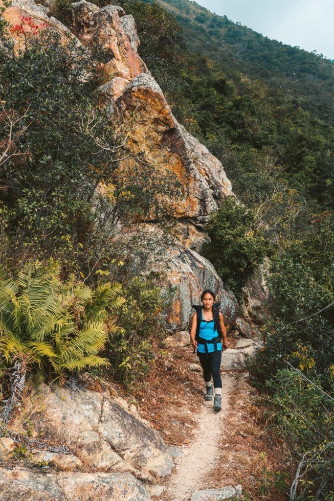 a woman walking up a trail in the mountains.