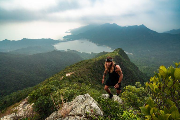 a man standing on top of a mountain next to a lake.