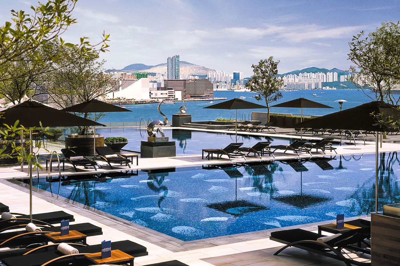 a large swimming pool with lounge chairs and umbrellas.