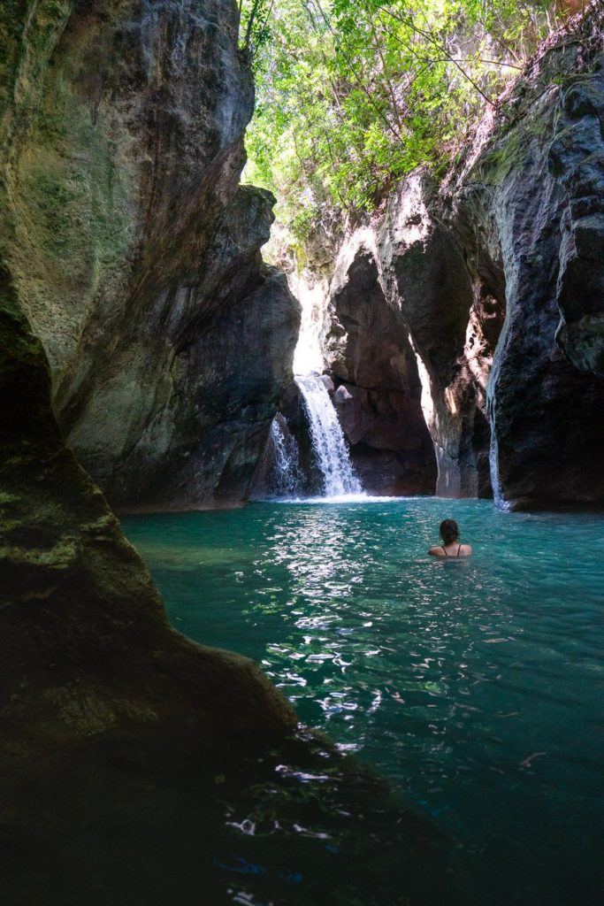 a person swimming in a pool in front of a waterfall.