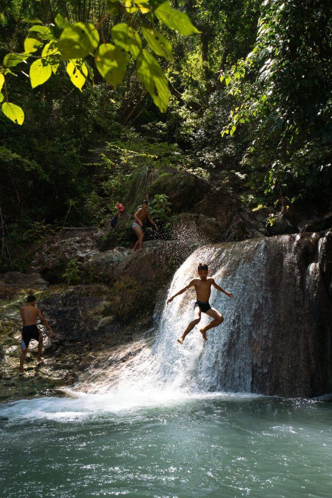 a group of people jumping into a waterfall.