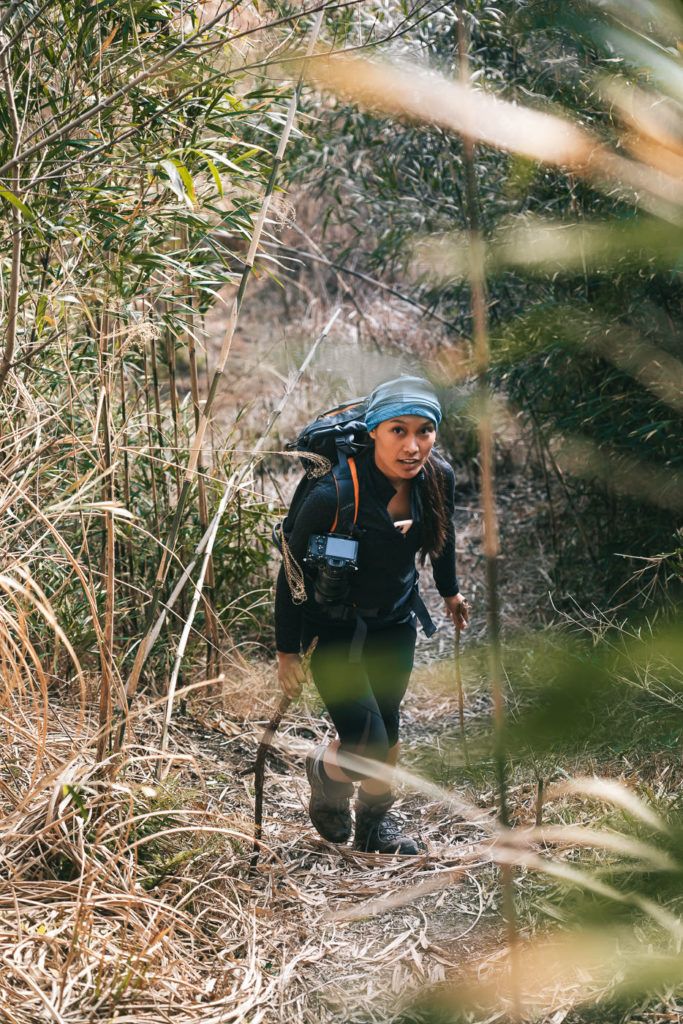 a woman with a backpack is hiking through the woods.