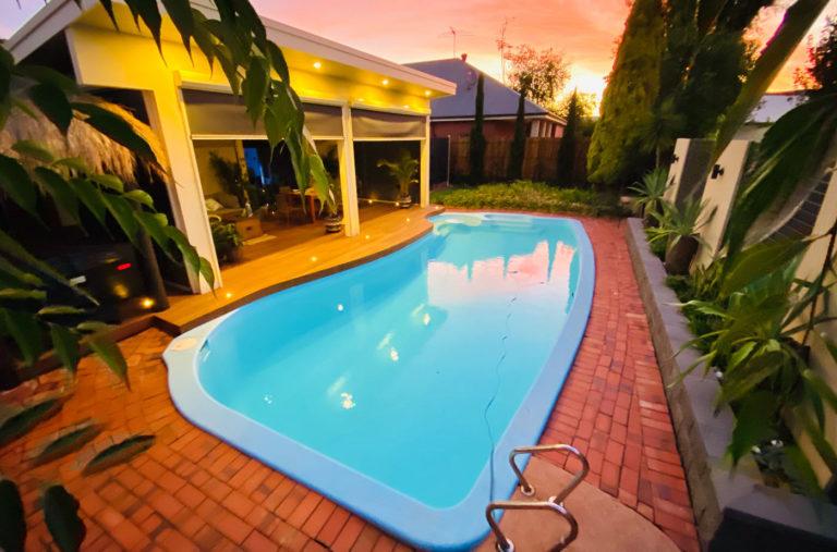 a pool in a backyard next to a house.