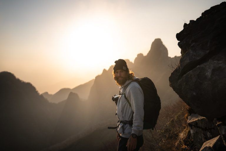 a man standing on top of a mountain with a backpack.