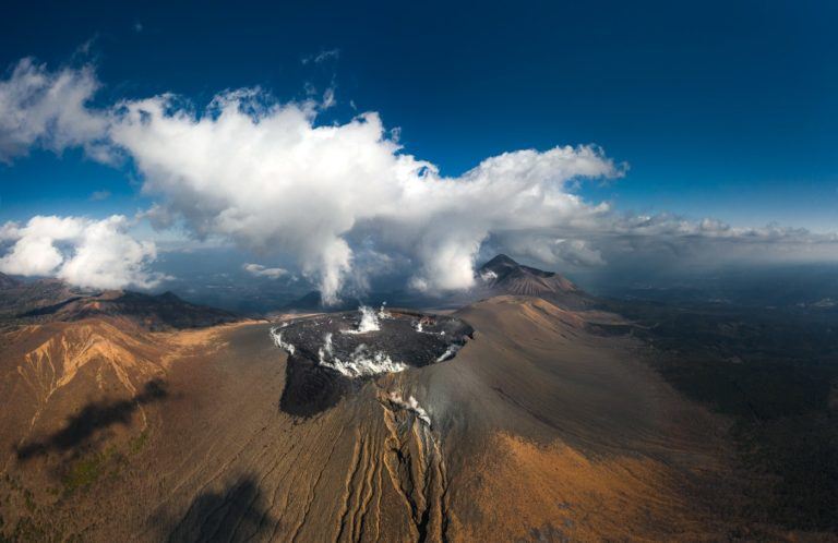 an aerial view of a volcano with steam coming out of it.
