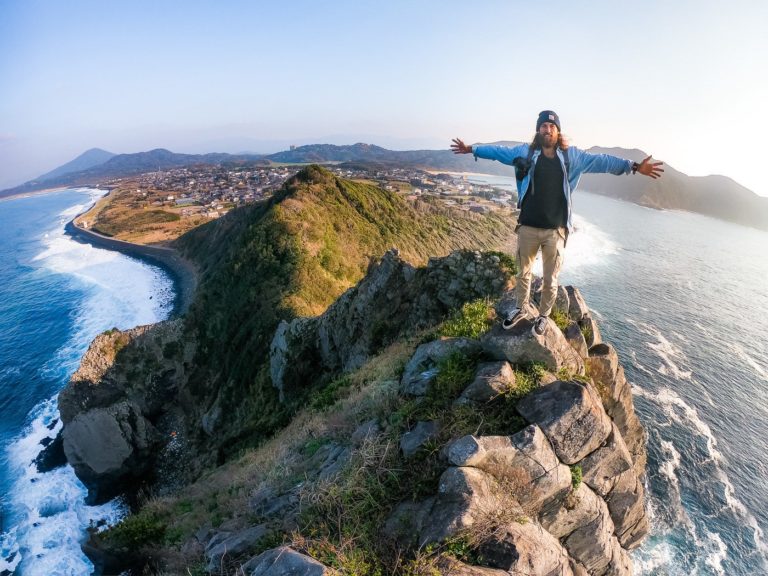 a man standing on top of a cliff next to the ocean.
