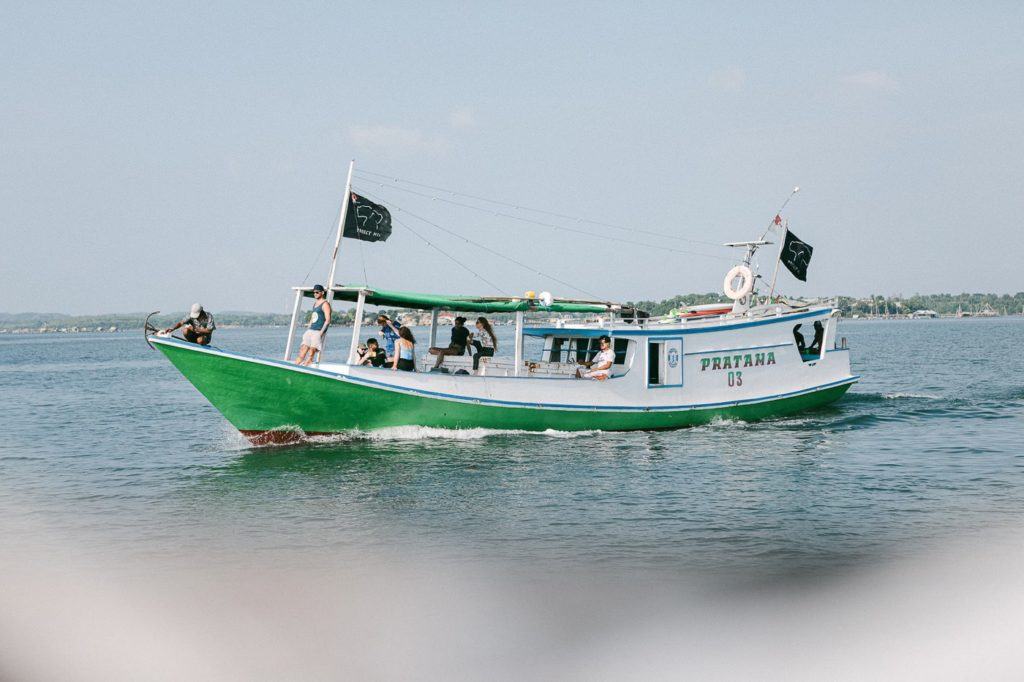 a green and white boat traveling across a body of water.