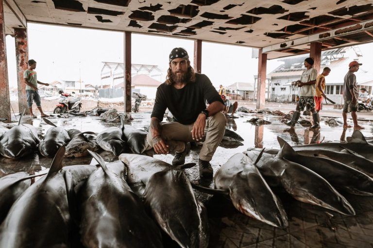 a man sitting on top of a pile of fish.