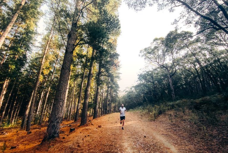 a man running down a dirt road in the woods.
