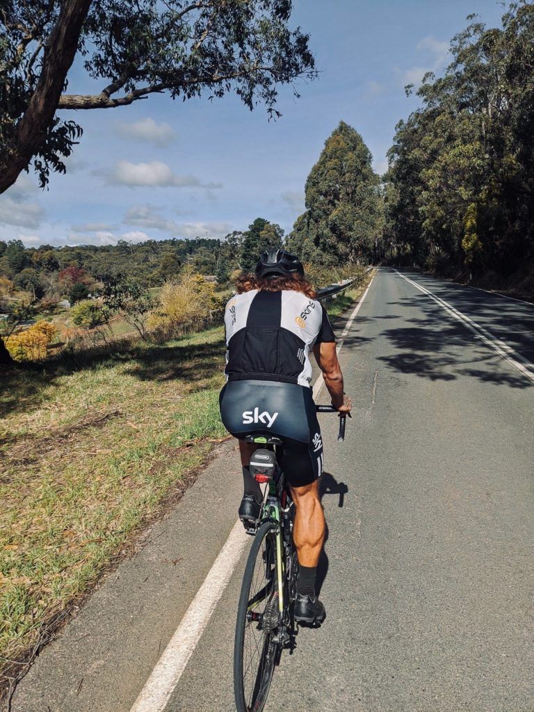 a man riding a bike down a country road.