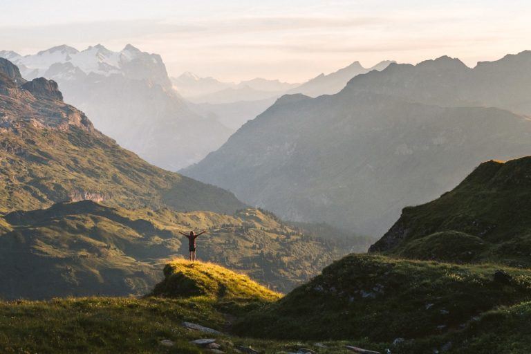 a person standing on top of a green hill.