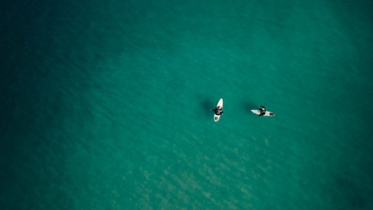 a couple of people riding on top of surfboards in the ocean.