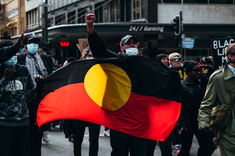 a group of people walking down a street holding a flag.