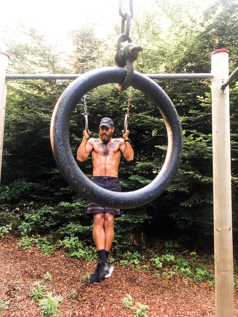 a man on a tire swing in the woods.
