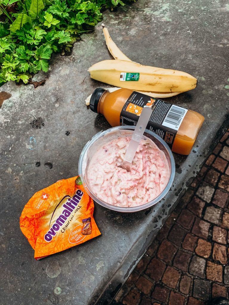 a bowl of food sitting on a sidewalk next to a banana.