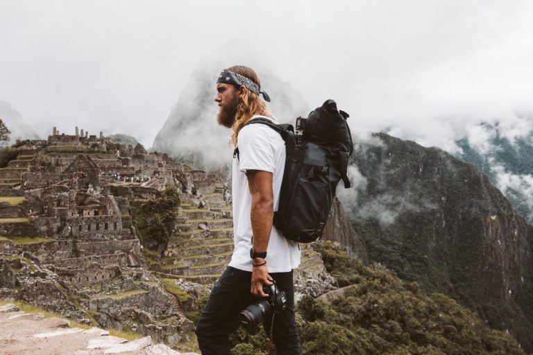 a man standing on top of a mountain with a camera.