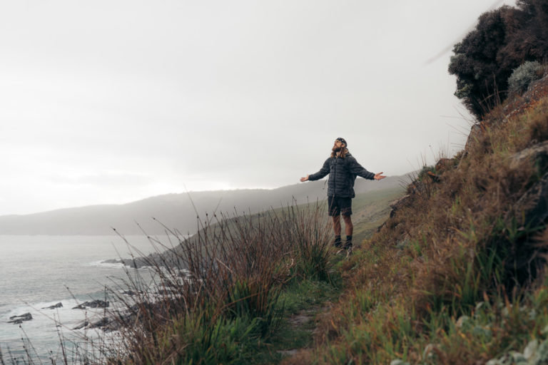 a woman standing on a cliff by the ocean.