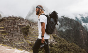a man standing on top of a mountain with a camera.