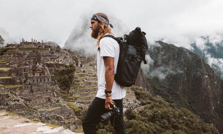 a man standing on top of a mountain with a camera.