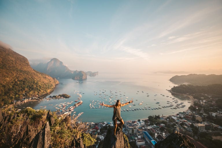 a woman standing on top of a cliff overlooking a body of water.