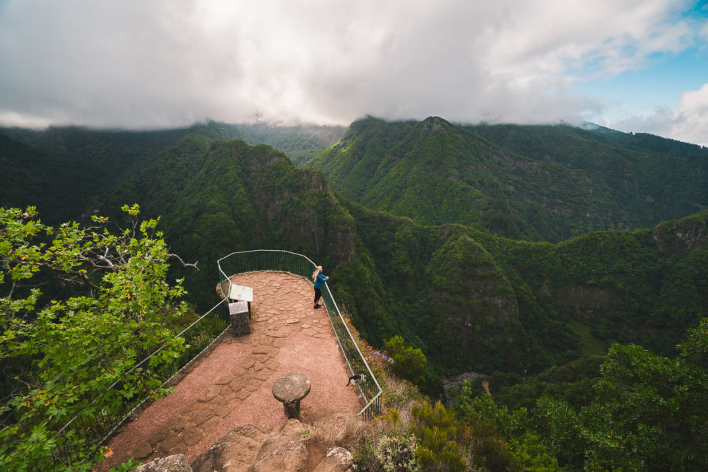 a man standing on top of a mountain next to a fence.