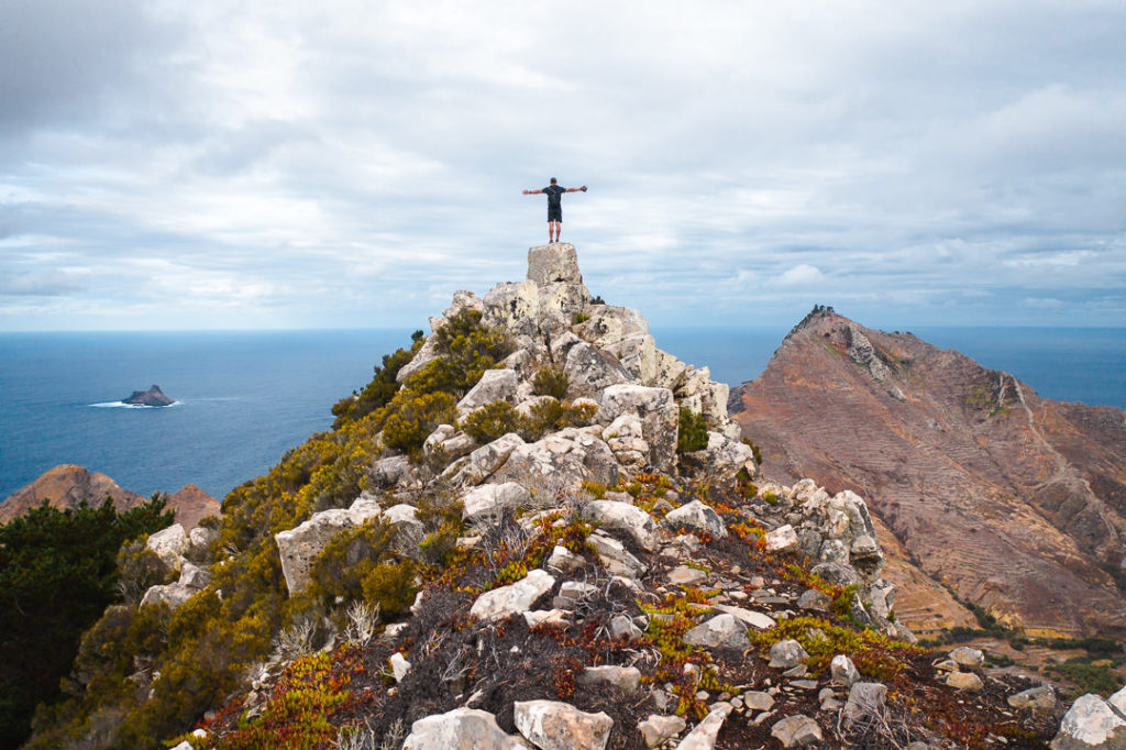 a person standing on top of a mountain with a cross.
