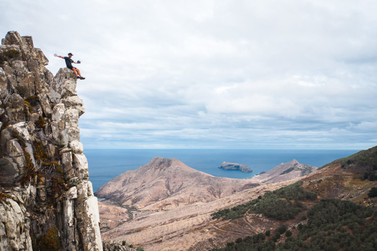 a man standing on top of a cliff next to the ocean.