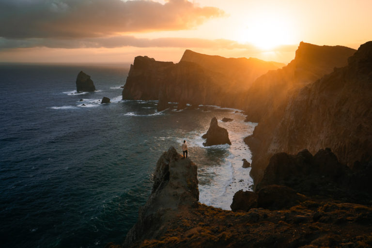 the sun is setting over the ocean near the cliffs.